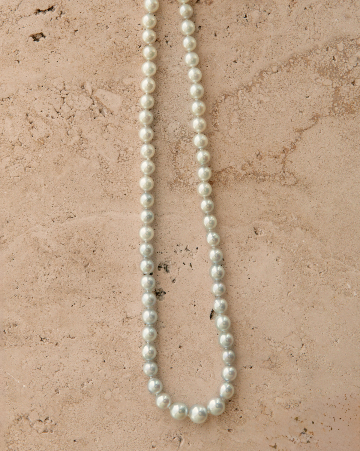 Pearl necklace on a textured beige surface