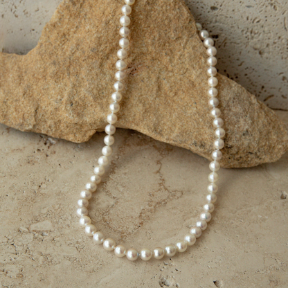 Pearl strand necklace on a textured stone surface