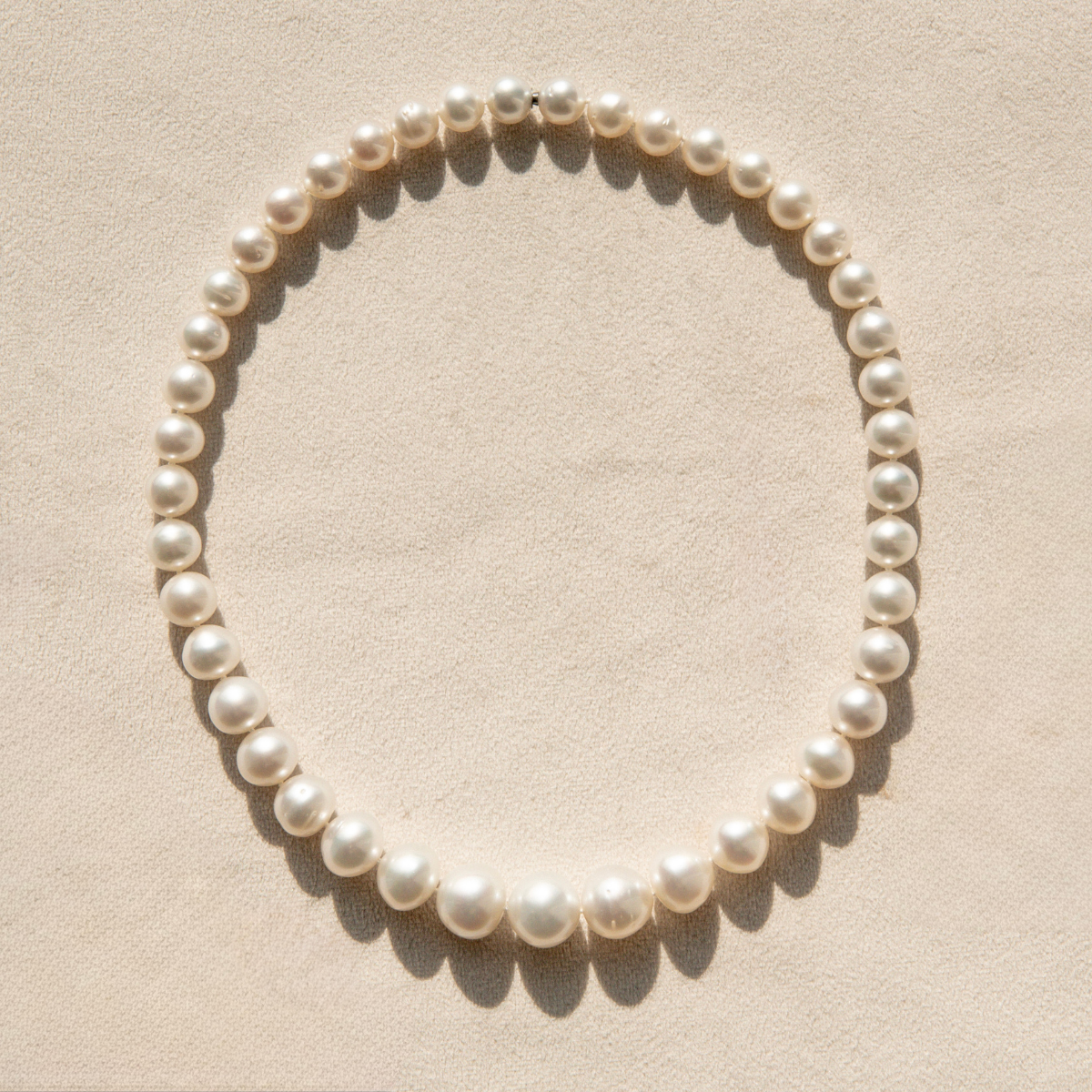 Pearl strand necklace on a beige background