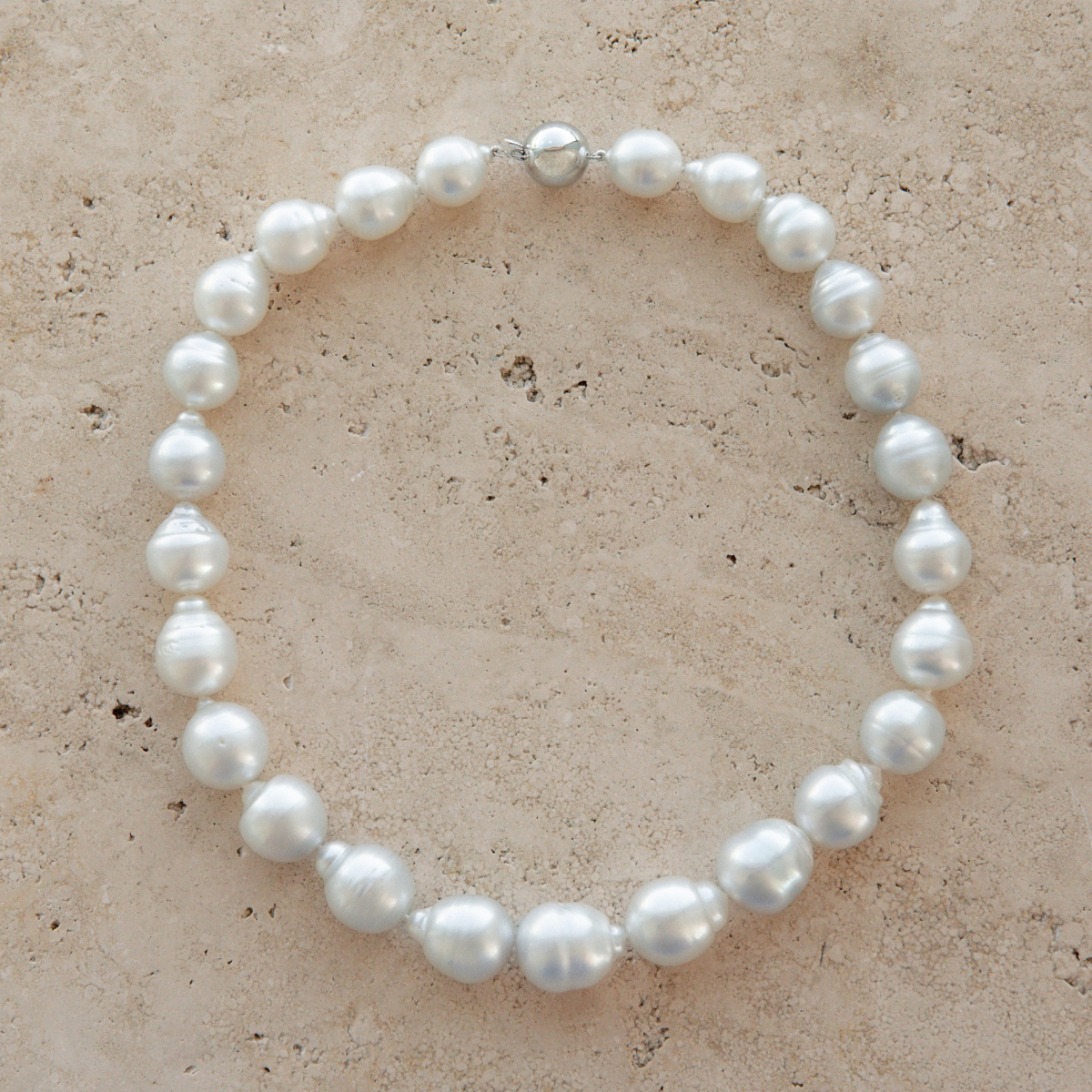 Pearl strand necklace on a textured beige surface