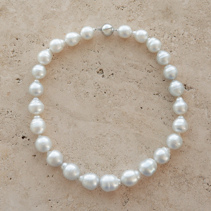Pearl strand necklace on a textured beige surface