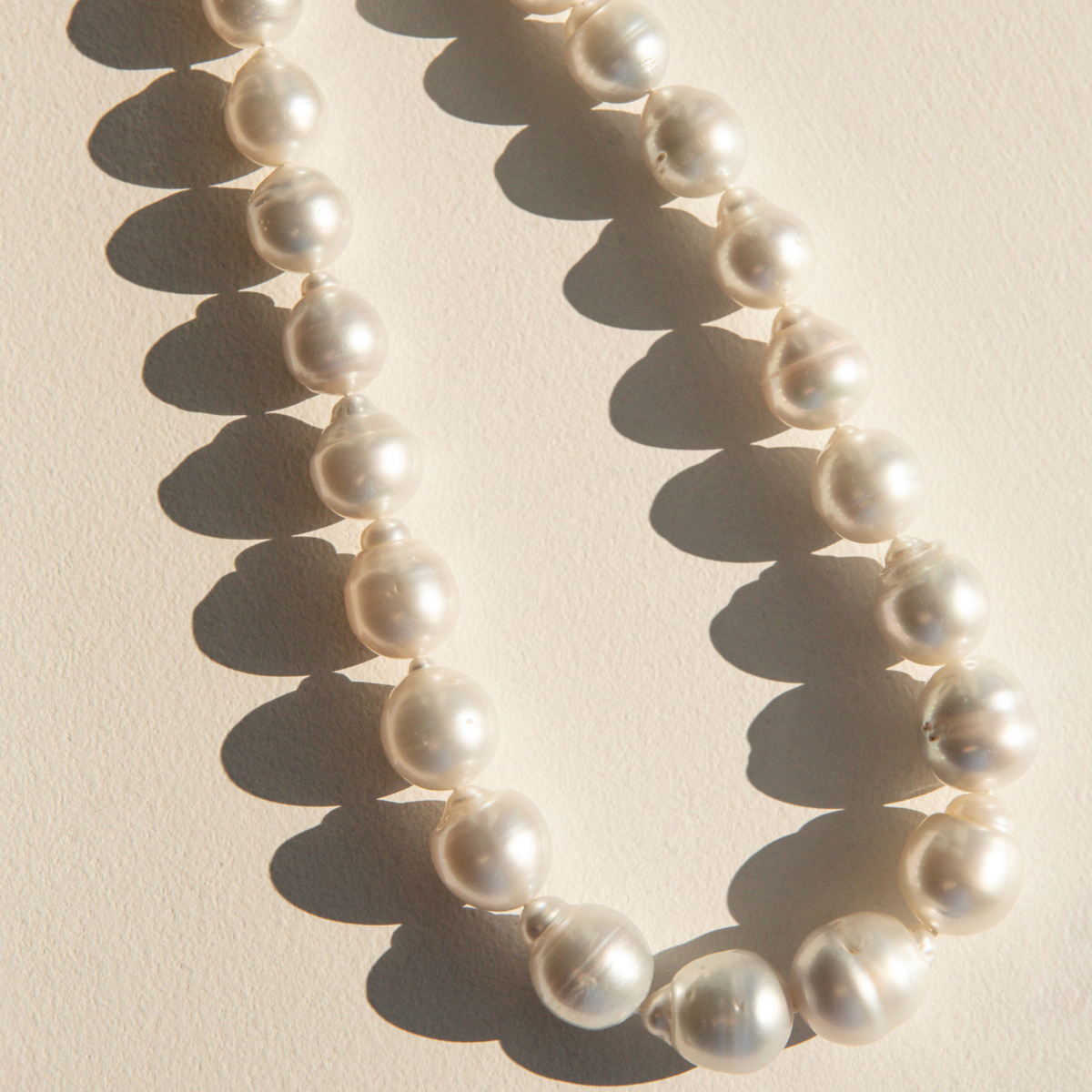 Pearl strand necklace on a beige background