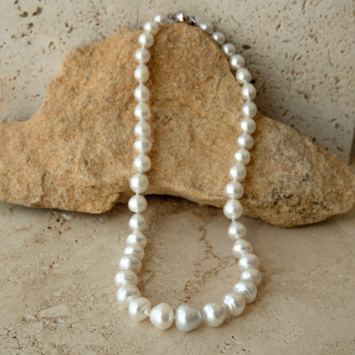 Pearl strand necklace on a textured stone surface