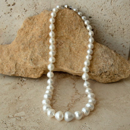 Pearl strand necklace on a textured stone surface