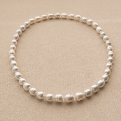 A single strand of Australian South Sea pearls arranged in a circle on a textured beige background.