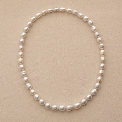 A strand necklace featuring Australian South Sea pearls arranged in a neat circle on a textured beige background.