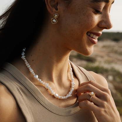 Woman wearing a keshi pearl necklace and earrings with a blurred natural background