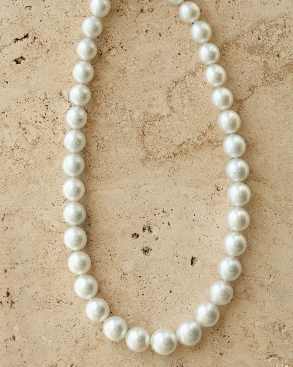 Pearl necklace on a textured beige surface