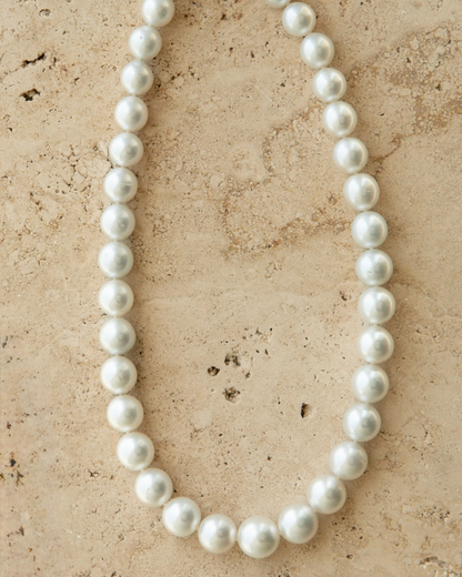 Pearl necklace on a textured beige surface