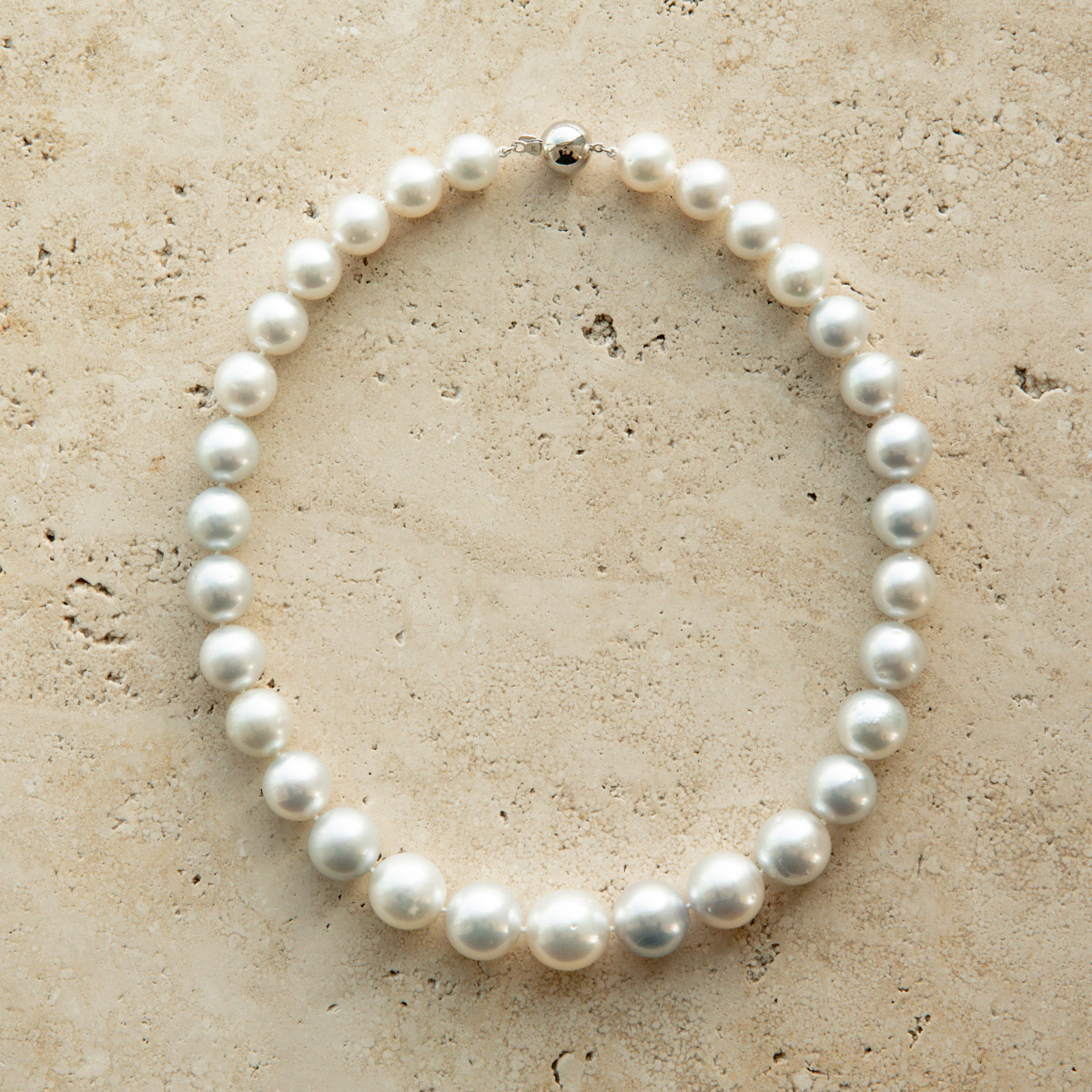 Pearl strand necklace on a textured beige surface