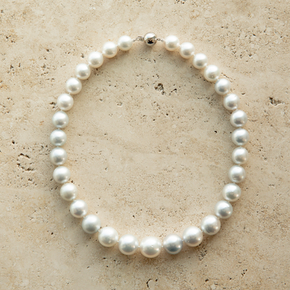 Pearl strand necklace on a textured beige surface