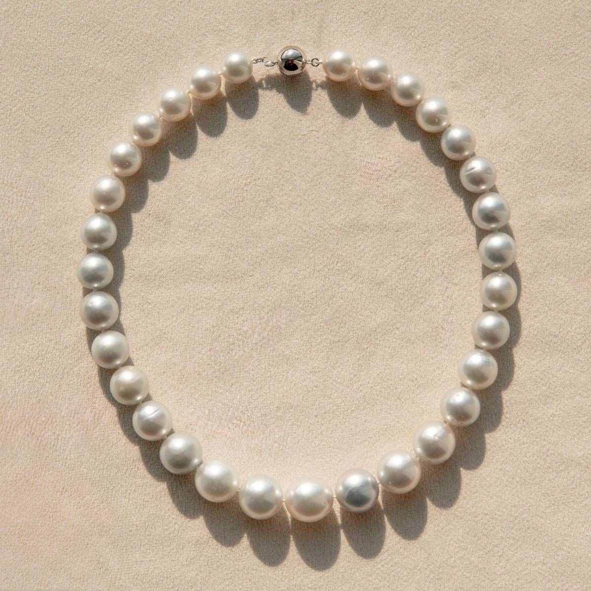 Pearl strand necklace on a beige background