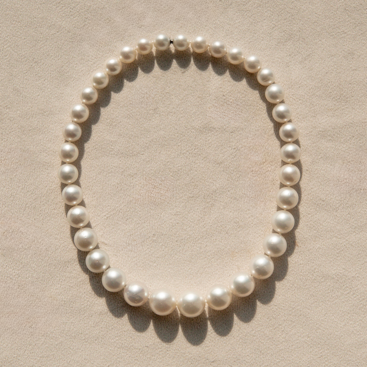 Pearl strand necklace on a beige background