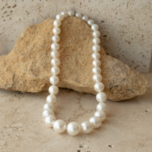 Pearl strand necklace on a textured stone surface