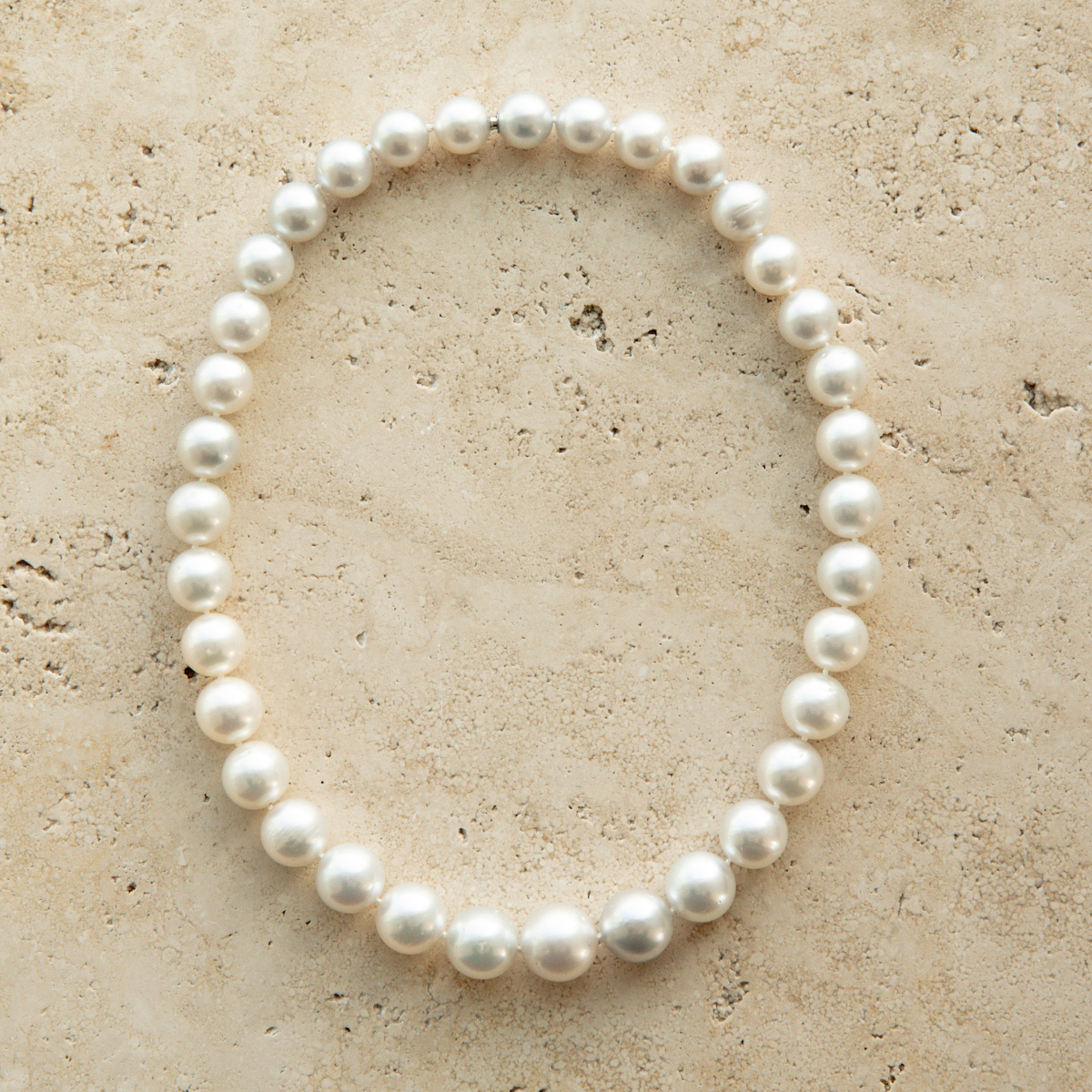 Pearl strand necklace on a textured beige surface