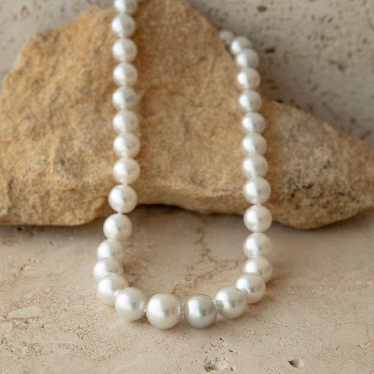 Pearl strand necklace on a textured stone surface