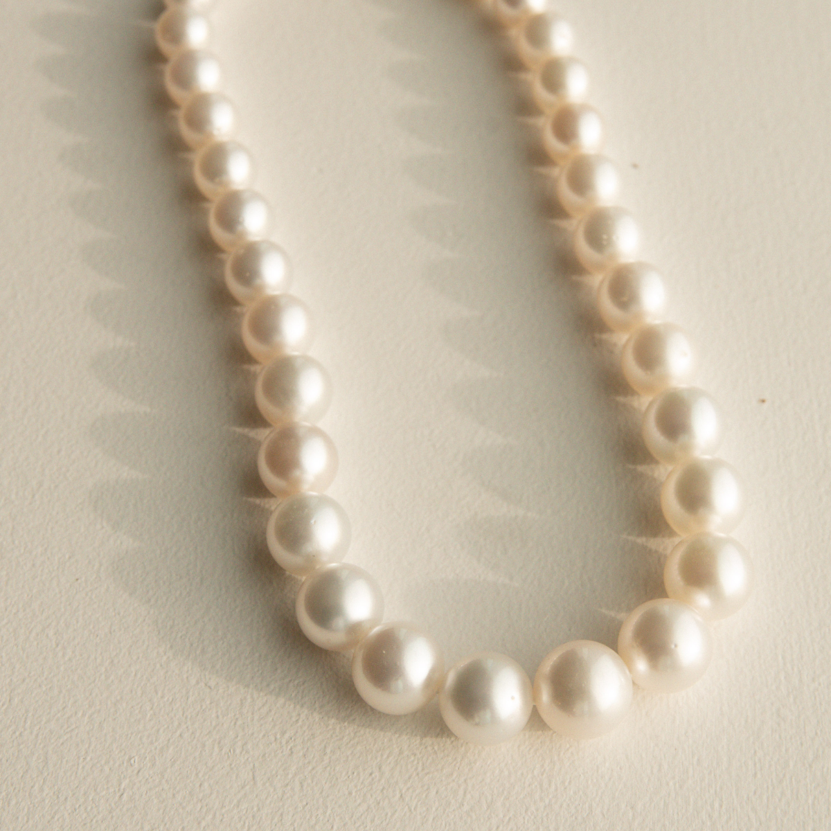 Round pearl necklace on a light beige background