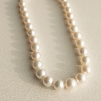 Round pearl necklace on a light beige background