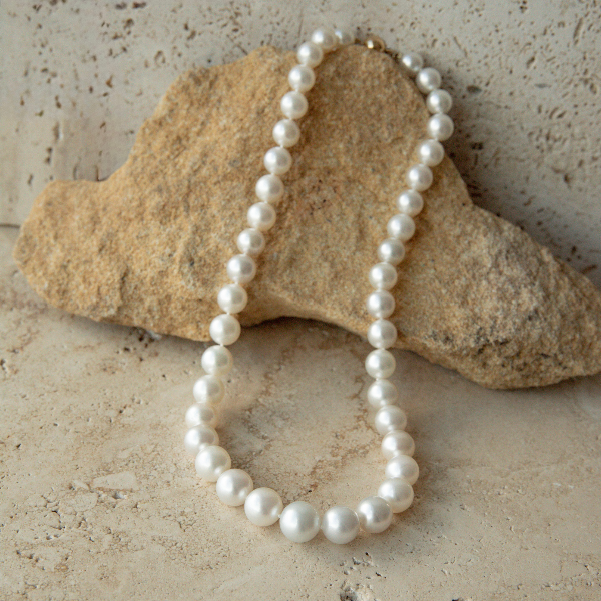 Pearl strand necklace on a textured stone surface