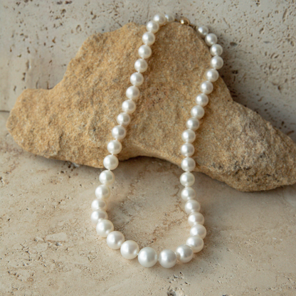 Pearl strand necklace on a textured stone surface