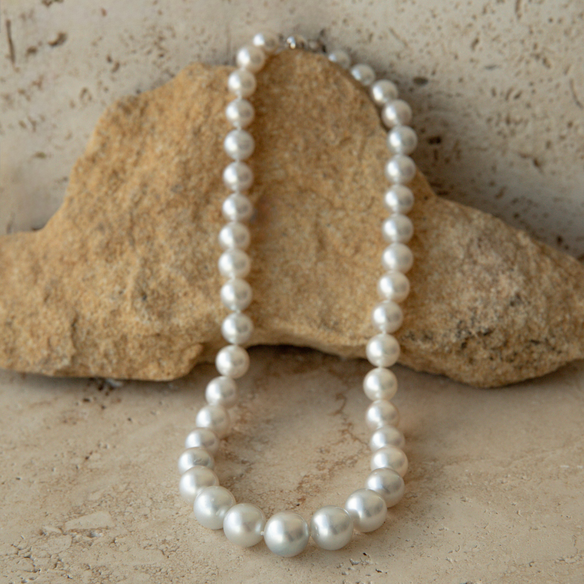 Pearl strand necklace on a textured stone surface