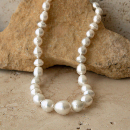 Pearl strand necklace on a textured stone surface