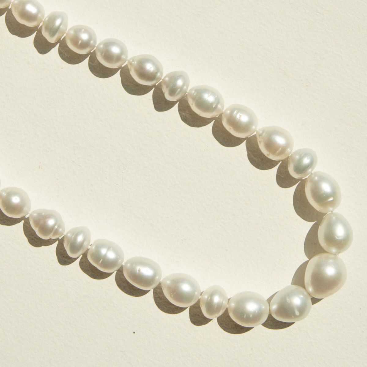 Pearl strand necklace on a light beige background