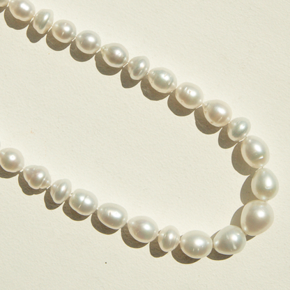 Pearl strand necklace on a light beige background