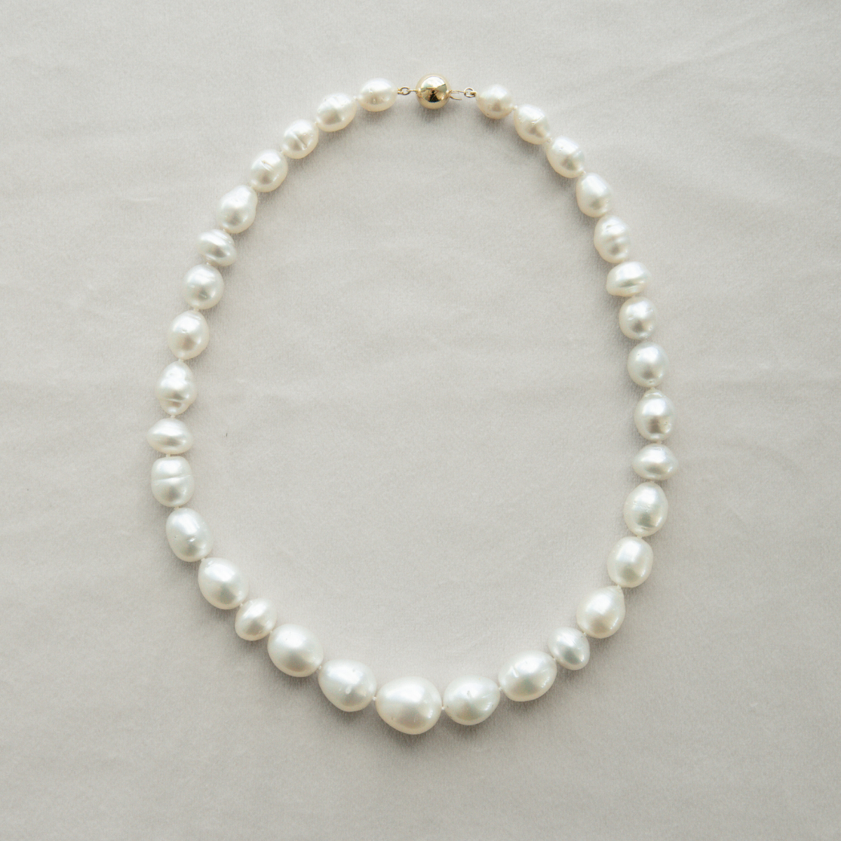 Pearl strand necklace on a light grey background
