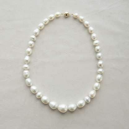 Pearl strand necklace on a light grey background