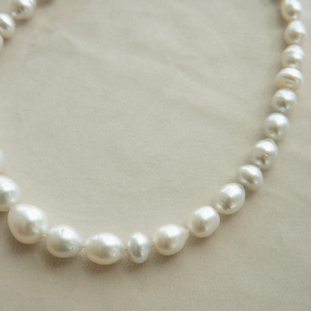 Pearl strand necklace on a light beige background