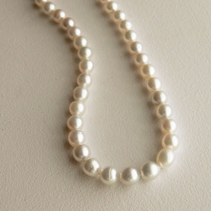 An Australian South Sea pearl strand necklace featuring Cygnet Bay grown pearls draped in a U-shape on a textured off-white background.