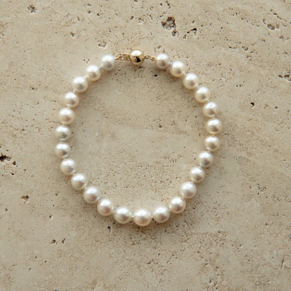 Pearl strand bracelet on a textured beige surface