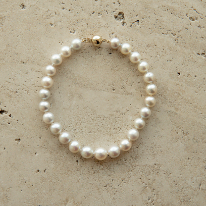Pearl strand bracelet on a textured beige surface