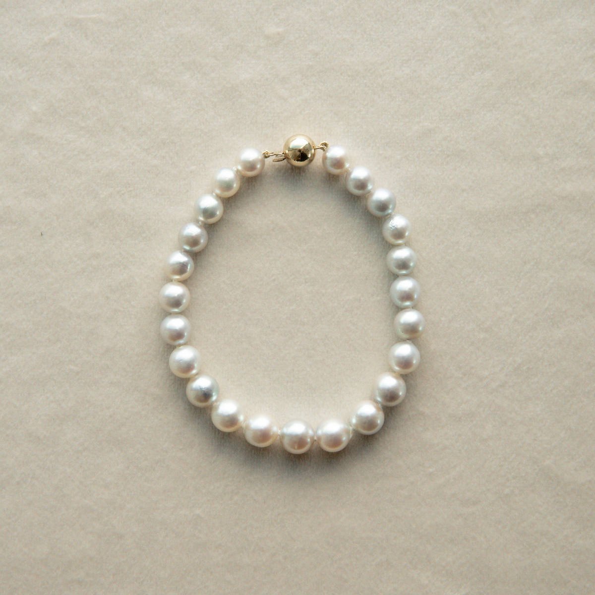 Pearl strand bracelet on a beige background