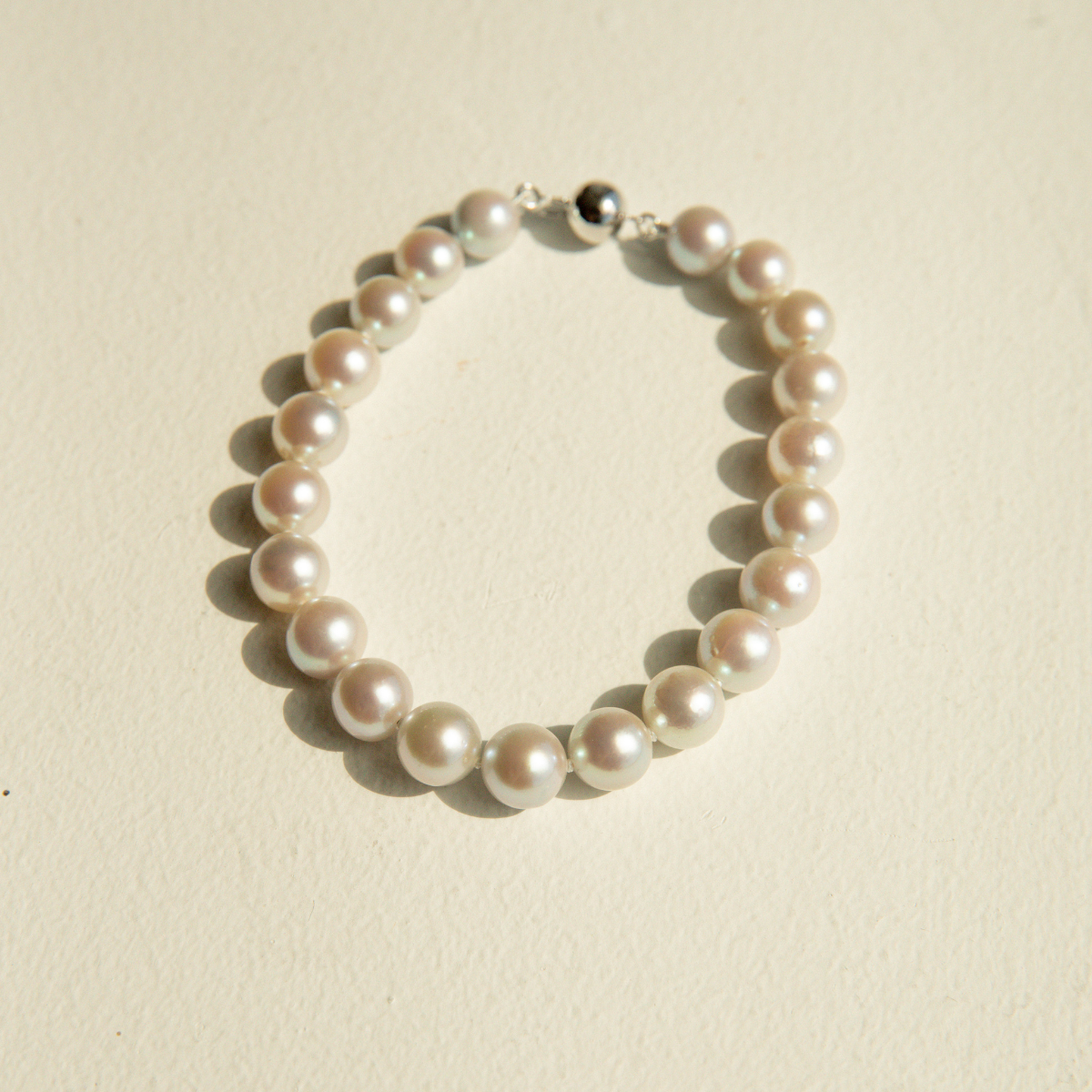 Pearl strand bracelet on a beige background