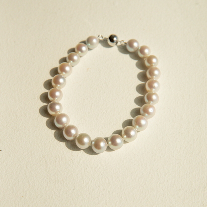 Pearl strand bracelet on a beige background