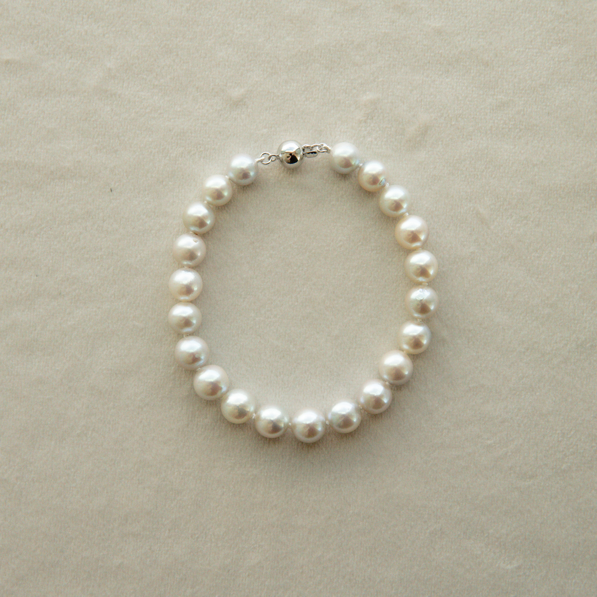 Pearl strand bracelet on a beige background
