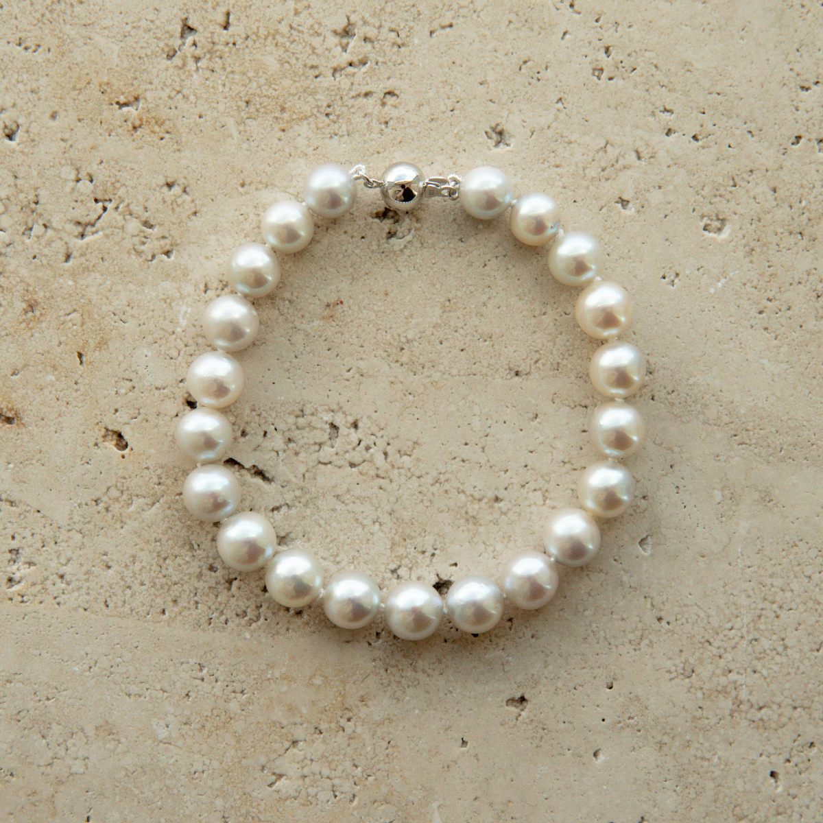 Pearl strand bracelet on a textured beige surface