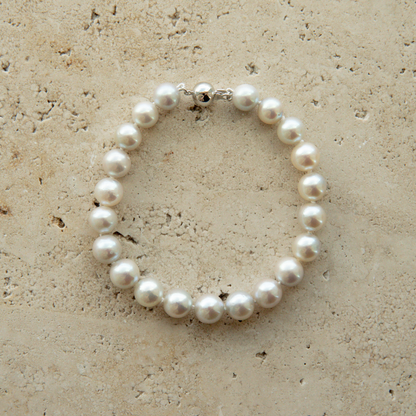 Pearl strand bracelet on a textured beige surface
