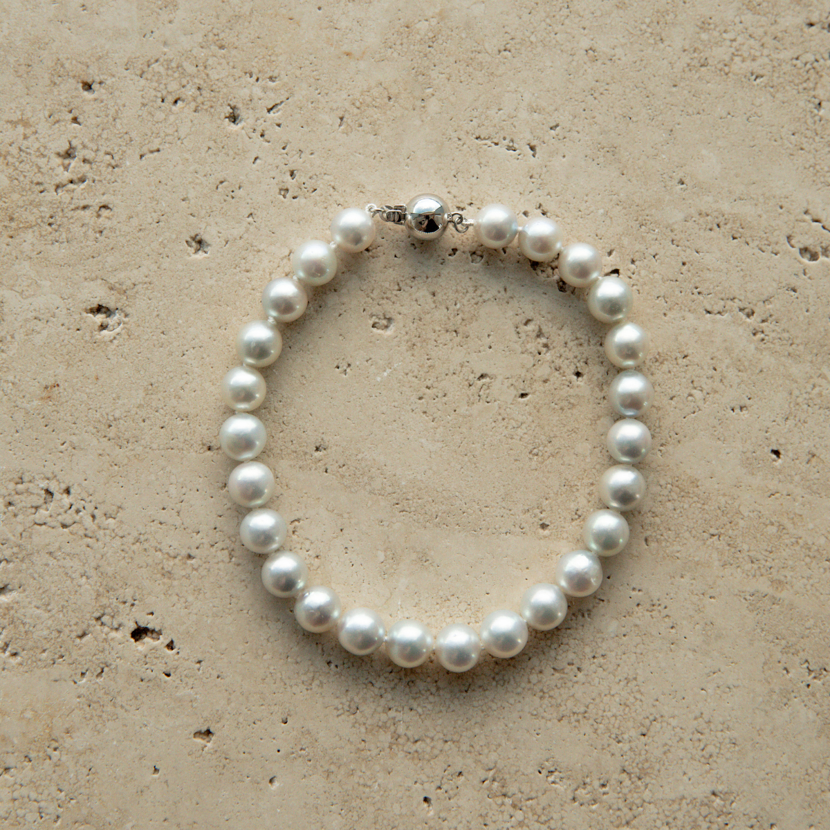 Pearl strand bracelet on a textured beige surface