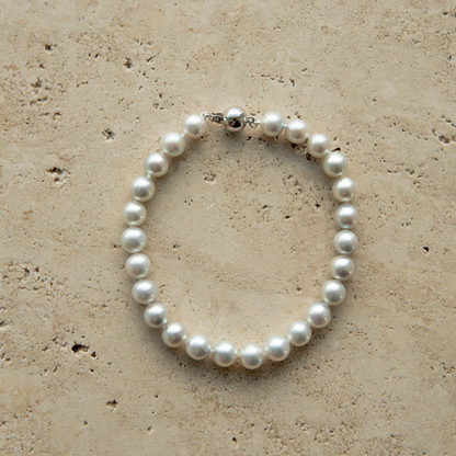 Pearl strand bracelet on a textured beige surface