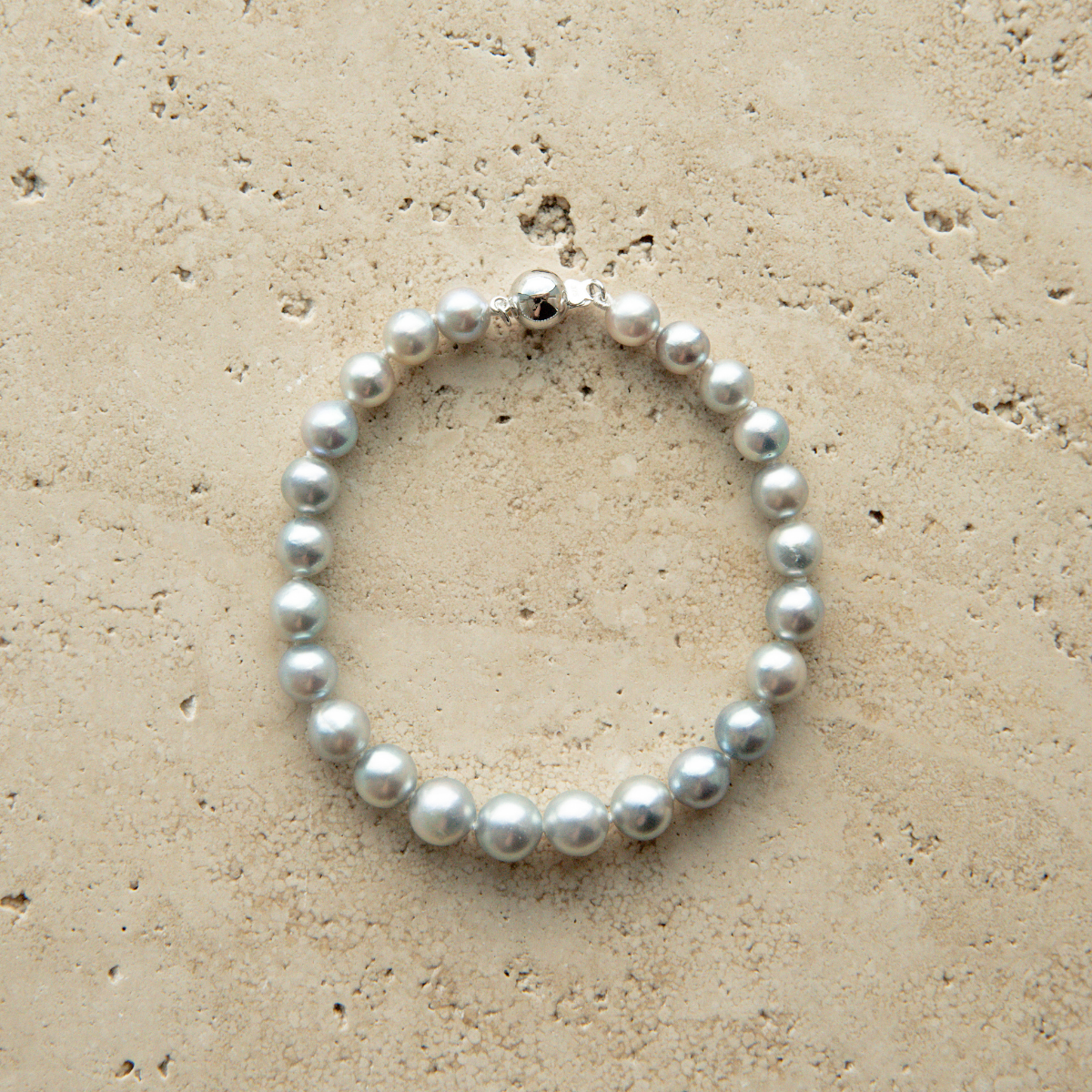Pearl strand bracelet on a textured beige surface