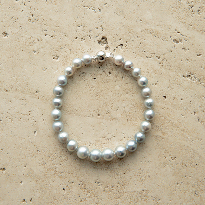 Pearl strand bracelet on a textured beige surface
