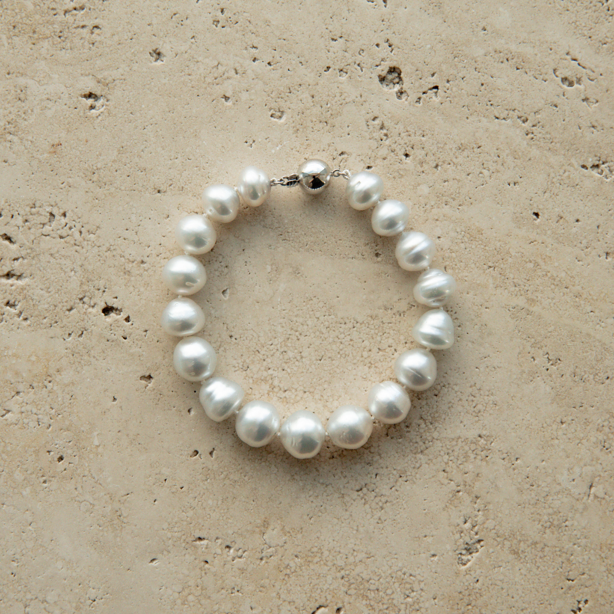 Pearl strand bracelet on a beige stone surface