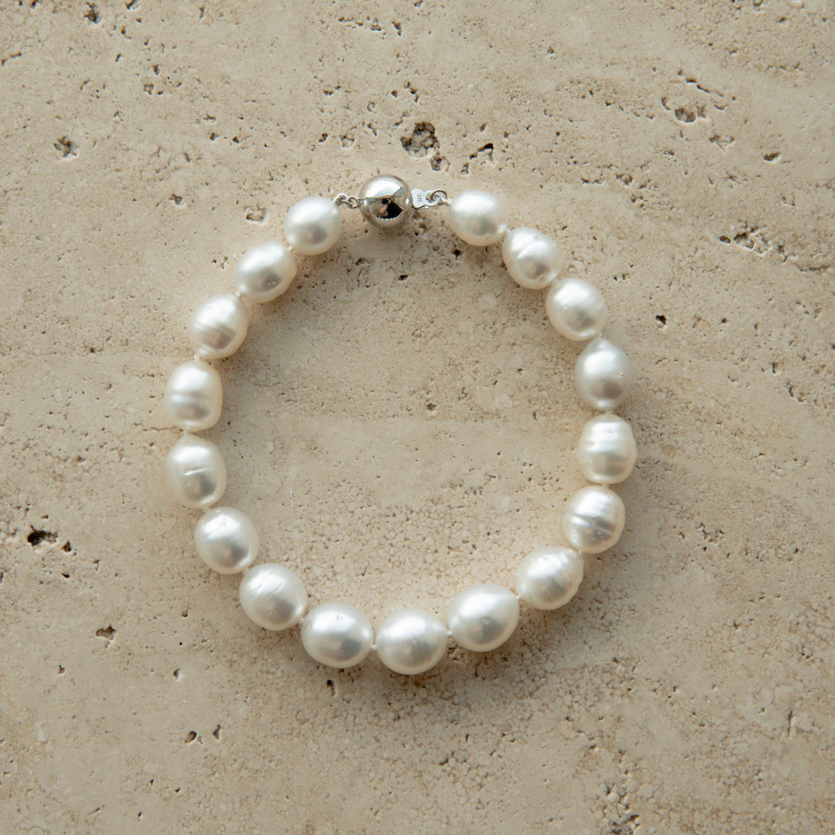 Pearl strand bracelet on a textured beige surface