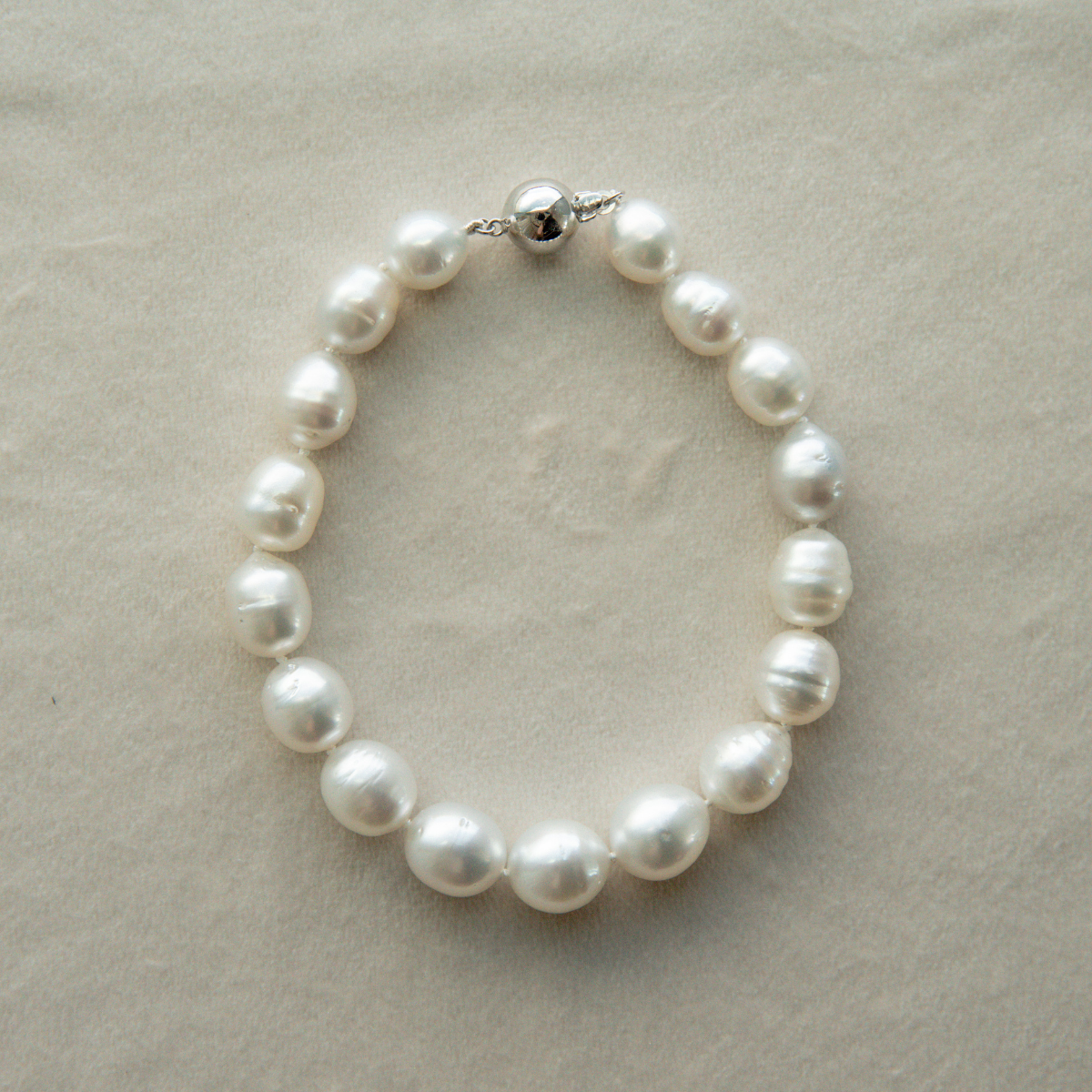 Circle pearl strand bracelet on a beige background
