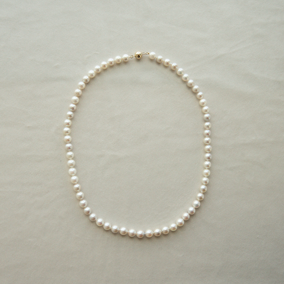 Pearl strand necklace on a light grey background