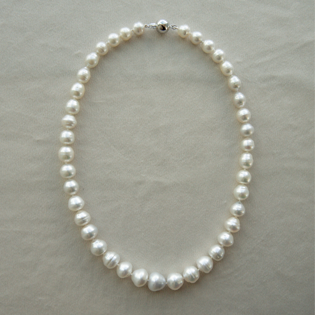 Pearl strand necklace on a light grey background