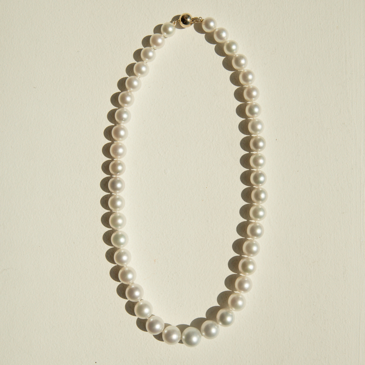 Pearl strand necklace on a beige background